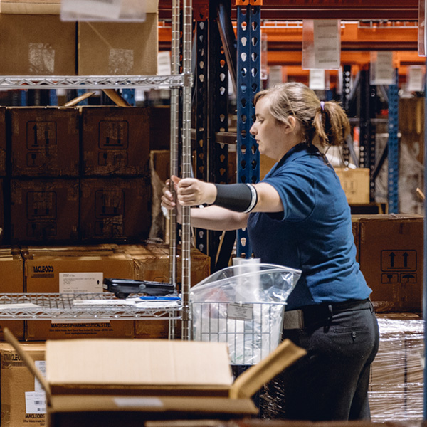 Female MMI Health Storage Worker Pushing a Cart inside Facility