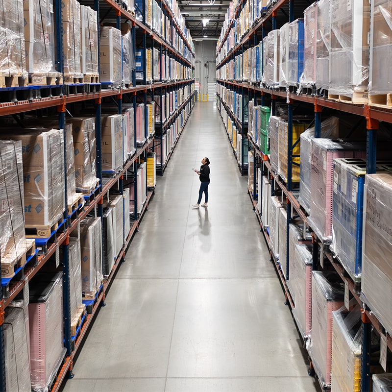 Warehouse Image Showing Stockpiled Inventory Neatly Stacked and Stored with Worker Monitoring