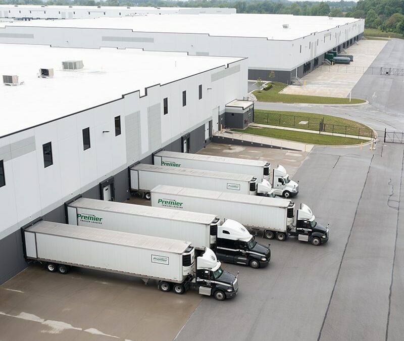 flyover view of large storage facilities with trailer trucks parked outside